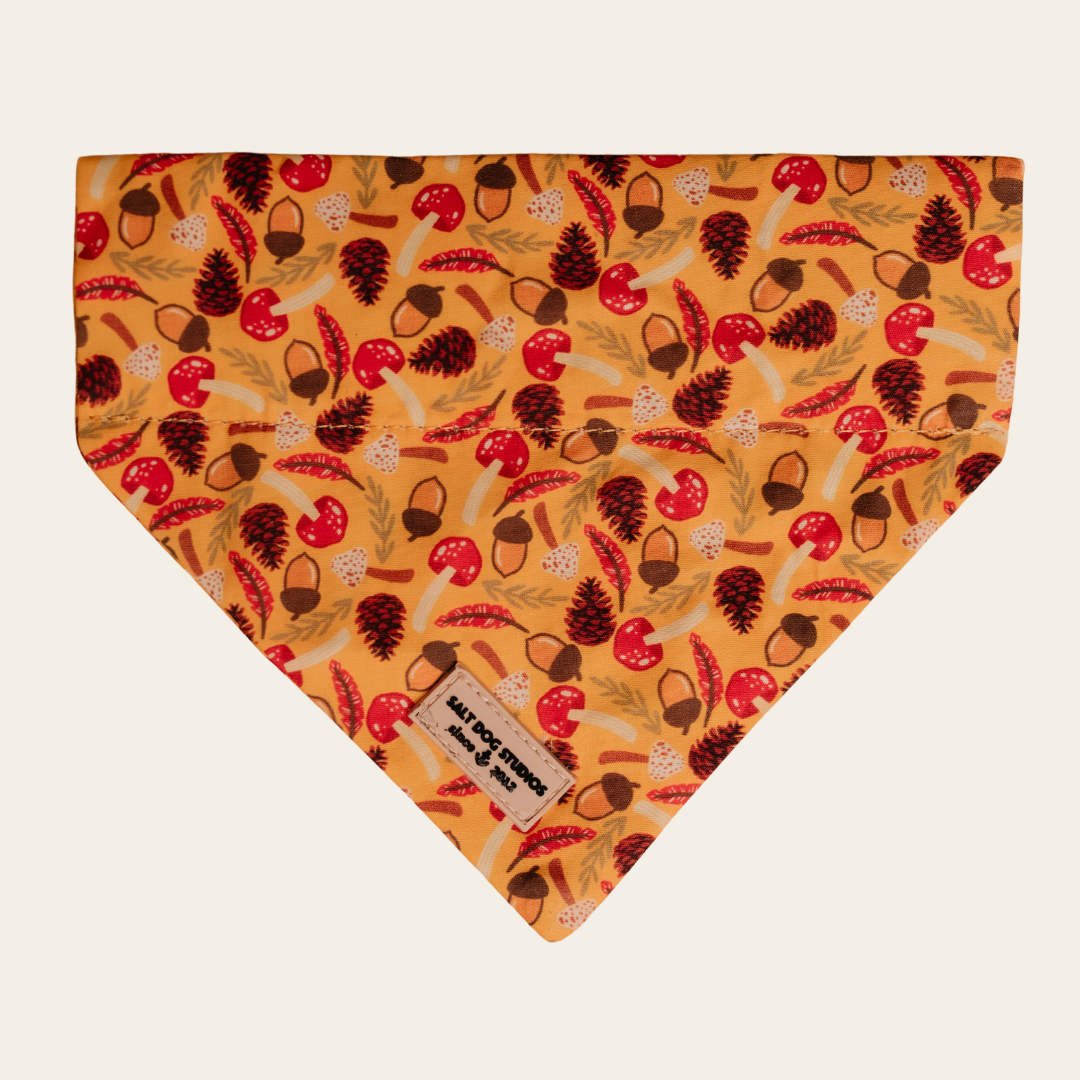 Woodland Treasure dog bandana with red and brown woodland motifs on mustard, shown flat