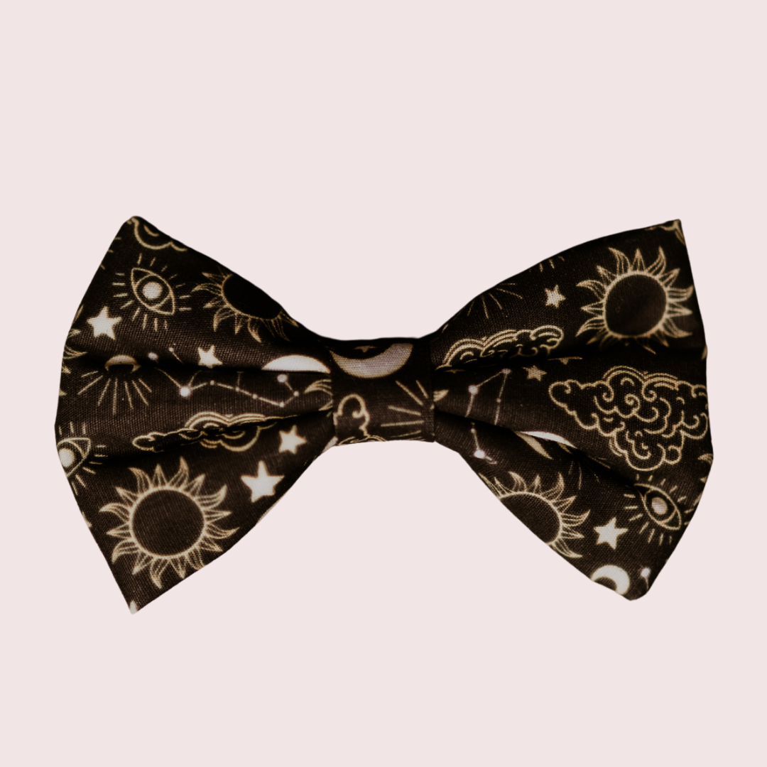 Celestial dog bow tie with gold suns, moons and stars on black, front view