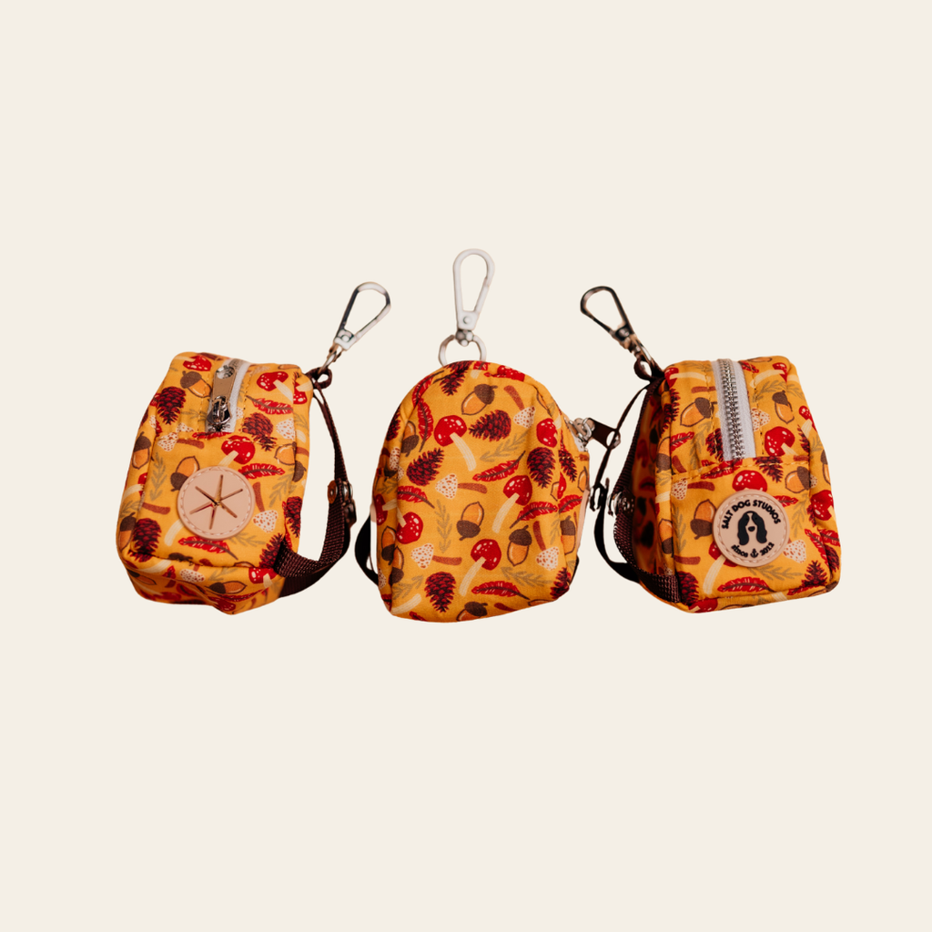 Woodland Treasure dog poo bag holder with red and brown woodland motifs on mustard, shown from three angles