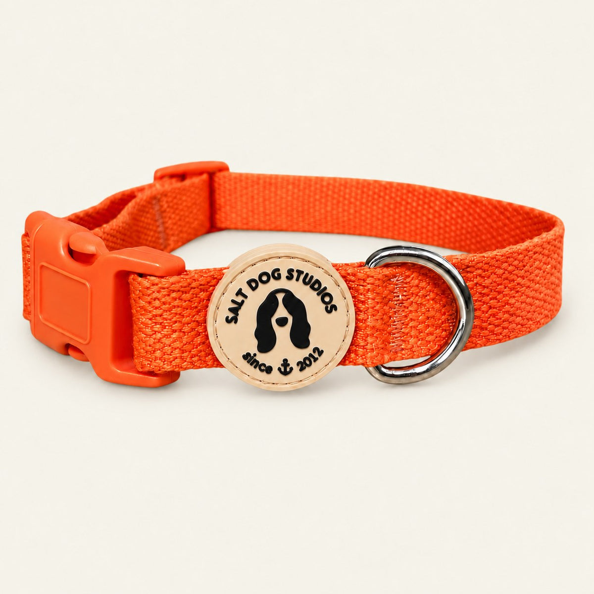 Salt Dog Studios plain clementine orange hemp dog collar, matching buckle and metal D-ring on a pale beige background.