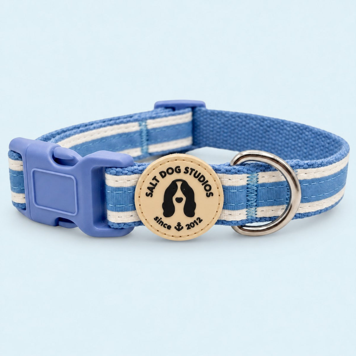 Salt Dog Studios striped cornflower blue hemp dog collar with white ribbon stripes, matching buckle and metal D-ring on a pale blue background.