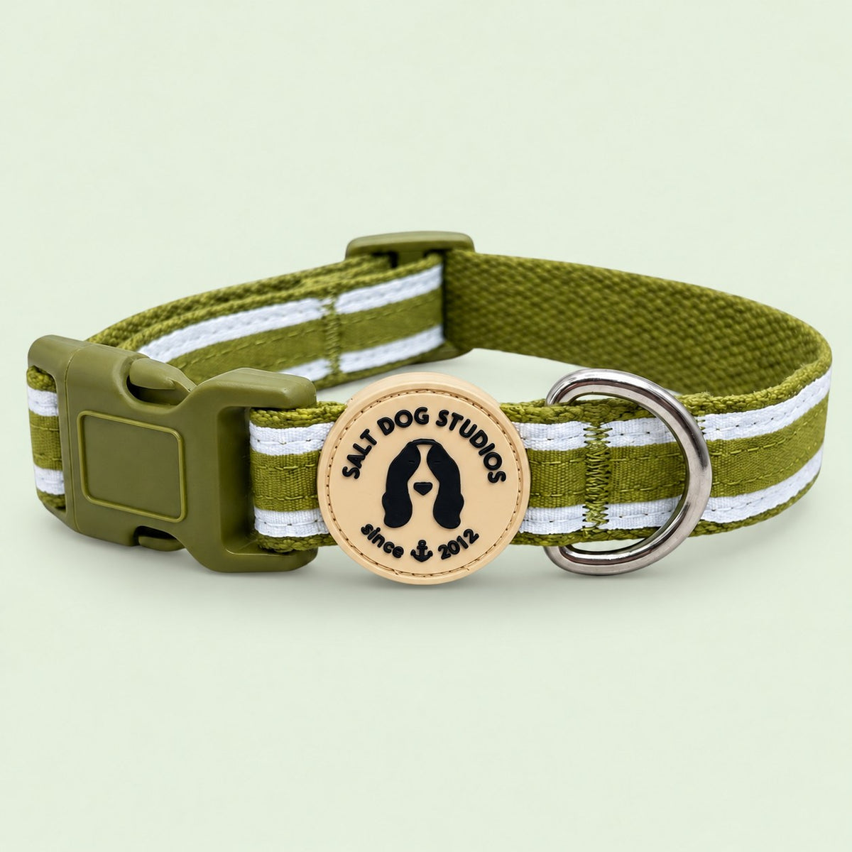 Salt Dog Studios striped grass green hemp dog collar with white ribbon stripes, matching buckle and metal D-ring on a pale sage green background.