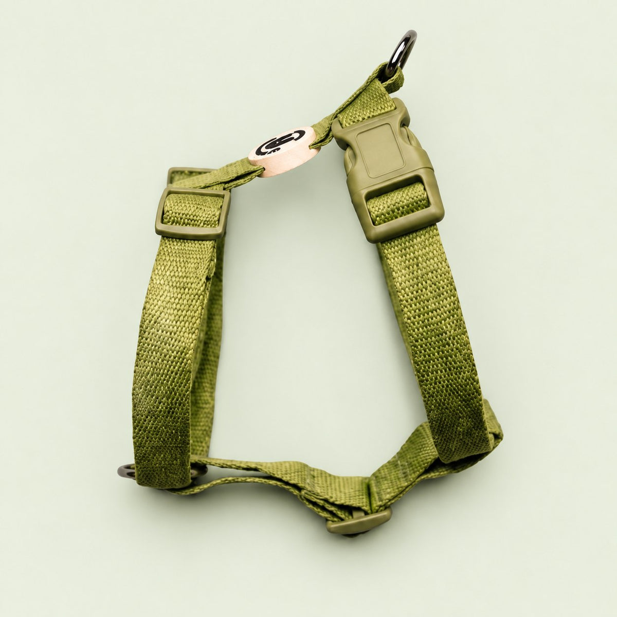 Salt Dog Studios plain grass green hemp dog harness with adjustable straps and matching buckle on a pale sage green background.
